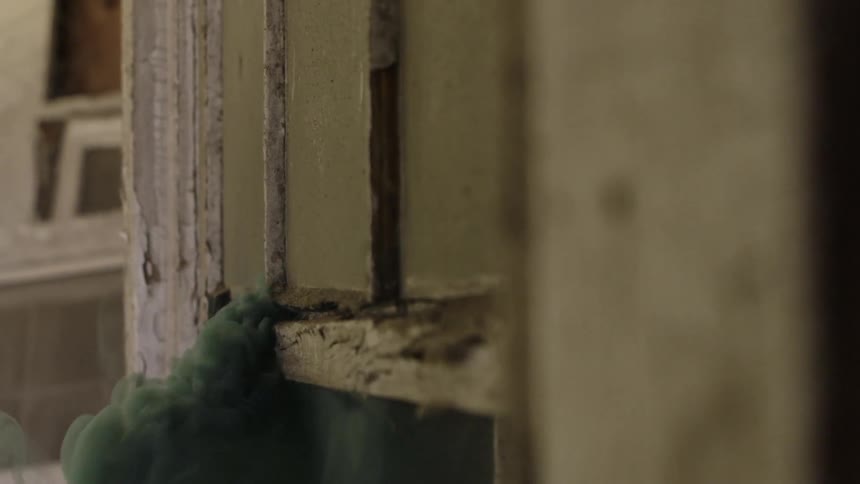 Smoke billows through a crack in a wall