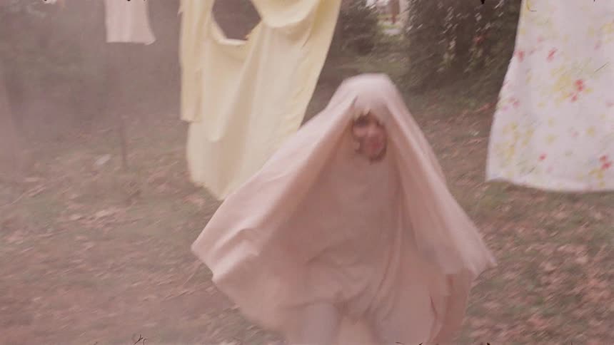 A child runs past a clothesline wearing a sheet