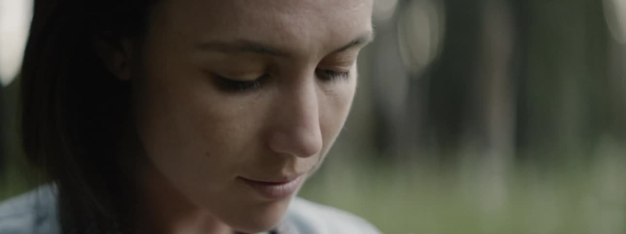 A woman looks down smiling in the yard