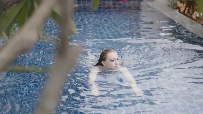A woman is swimming in a pool in daylight