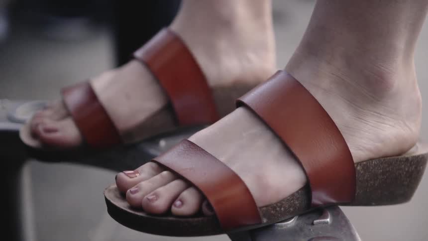 Sandaled feet step up onto a round metal object