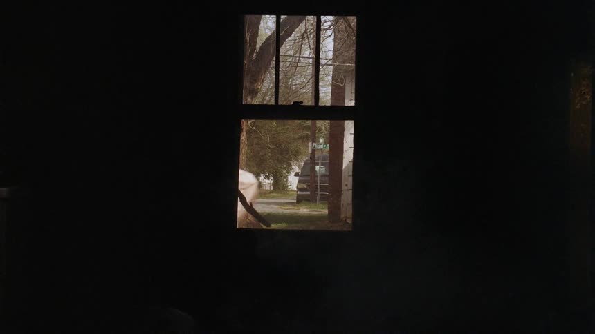 People walking outside past a window of a dark house
