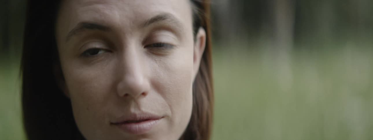 A woman blinks and looks around outside
