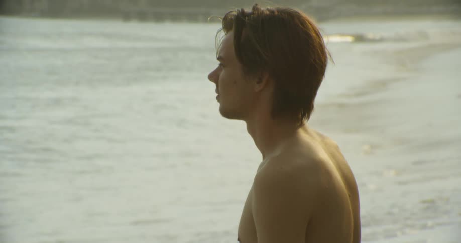A man looks out onto the water from the beach