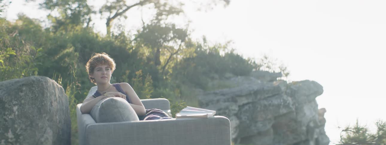 A woman sits on a sofa in mountains