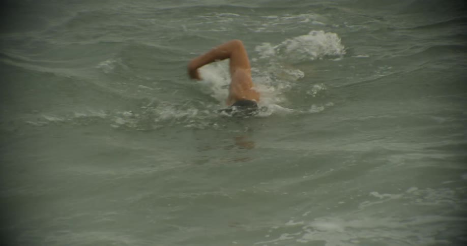 A man is swimming in the ocean in daylight