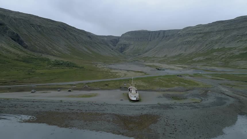 The boat is on the soil near the mountain
