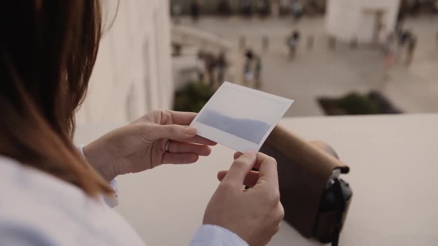 The woman is looking at a polaroid