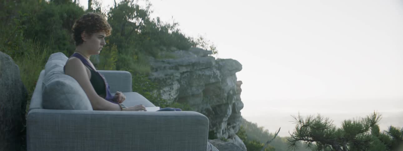 Woman sits on an outdoor sofa and closes her laptop