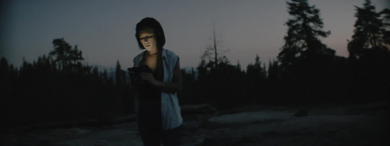 Woman looks at her cell phone as she stands in the dark outside