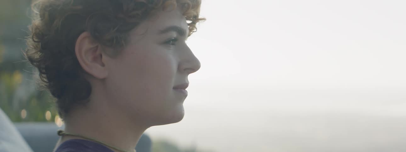 A woman looks out from atop a mountain