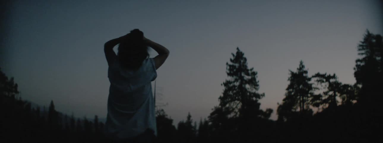 A woman looks up at the sky and pushes her hair back