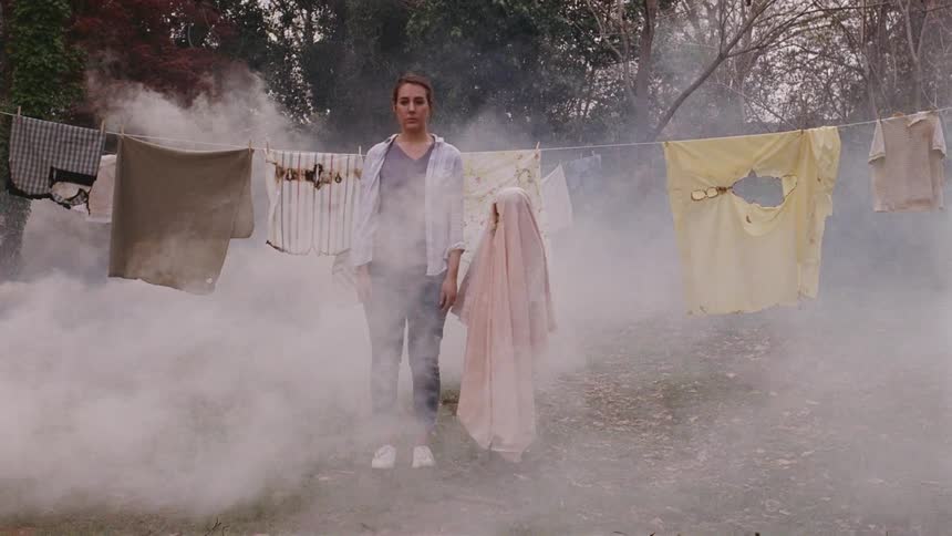 A woman stands by a kid wearing a sheet