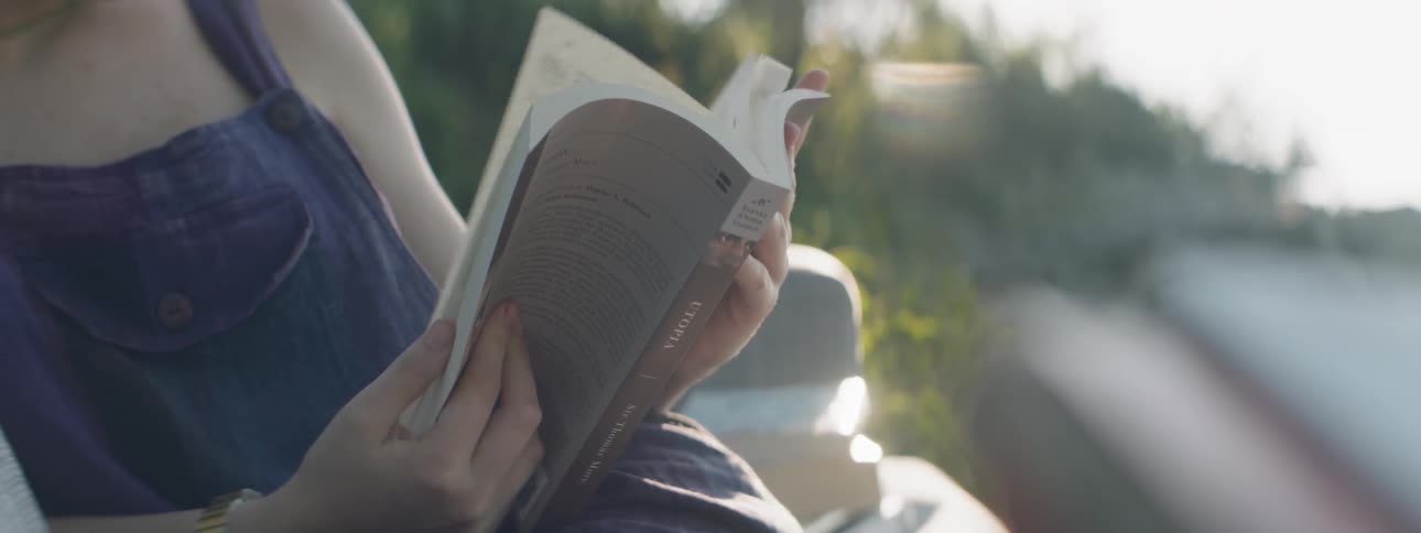 A woman is flipping through a book in the sun
