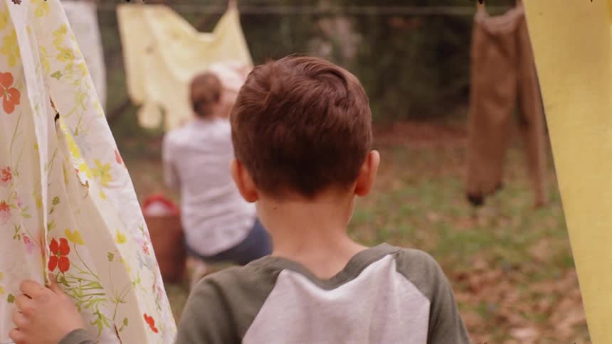 A child walks over to a parent hanging clothes