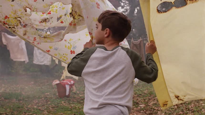 Woman hangs clothes on the line as a young boy approaches