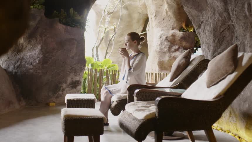 A woman drinks outside in a chair