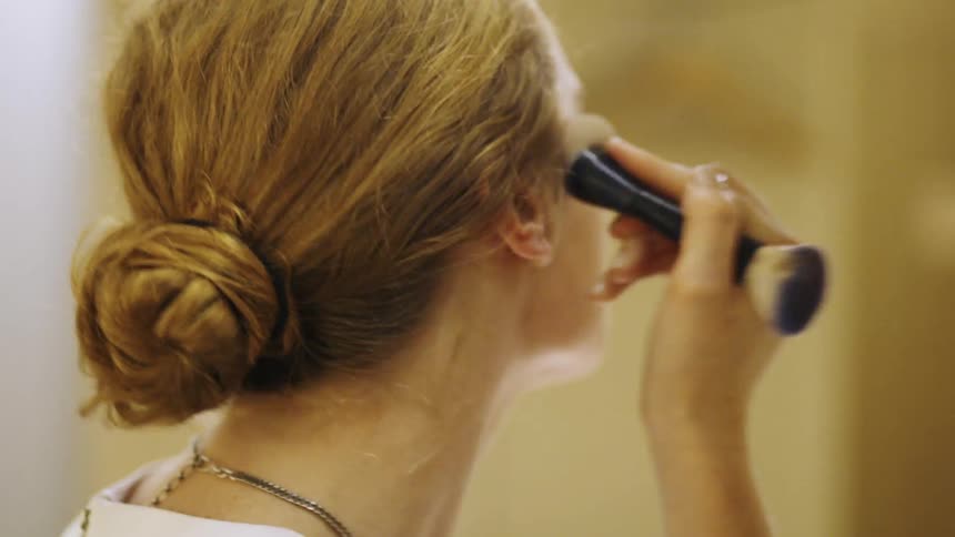 A woman is applying makeup