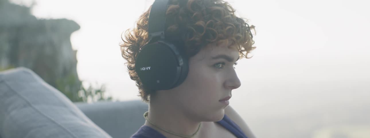 A woman listens on headphones outside
