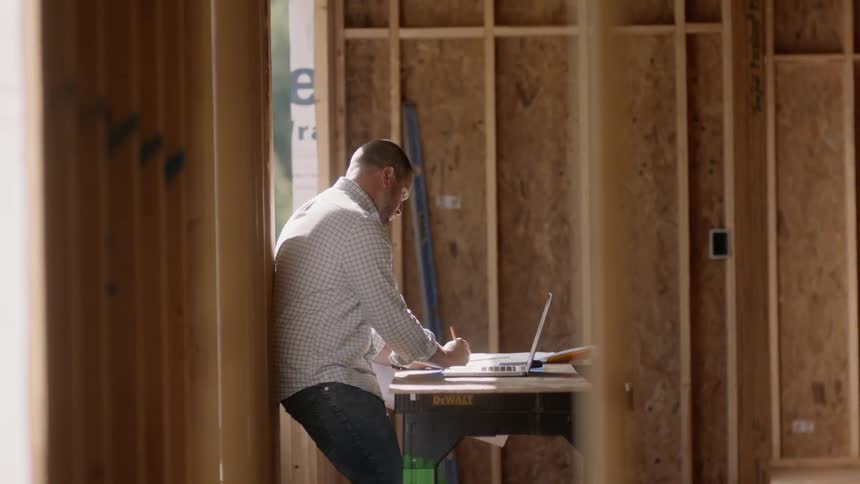 A man works on a laptop at a construction site