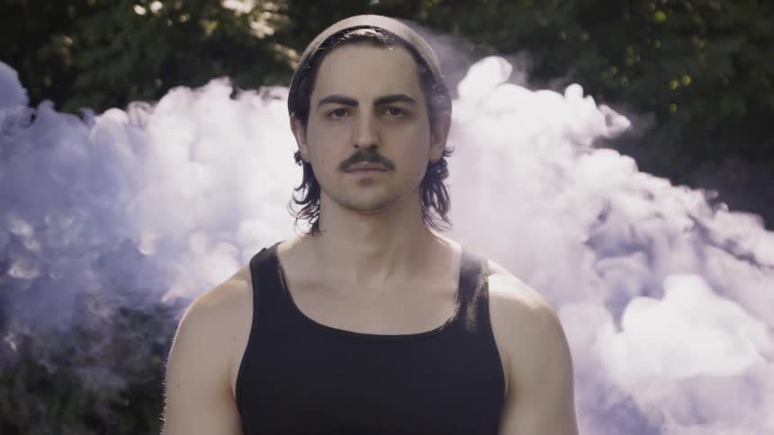A man stands by the trees as smoke passes