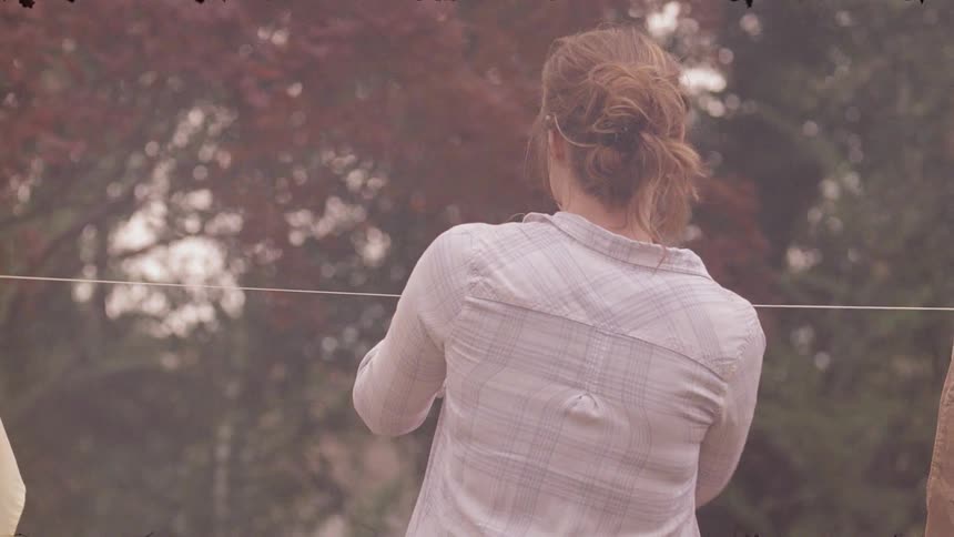A woman is hanging clothes in the yard