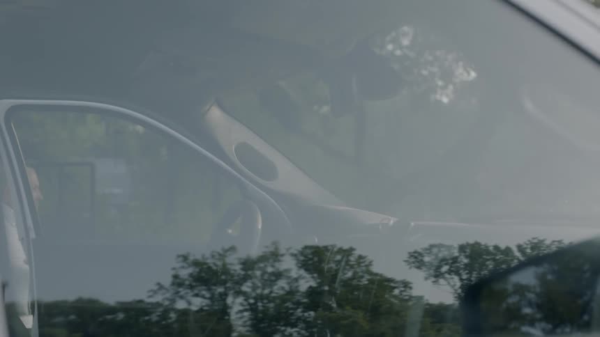 A man picks up blueprints and paperwork before exiting his truck during the day