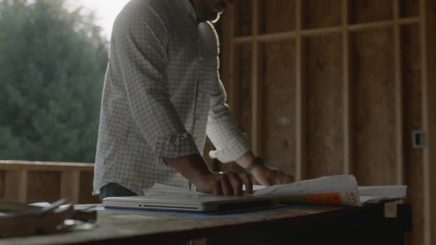 A man unfurls blueprints on a construction site