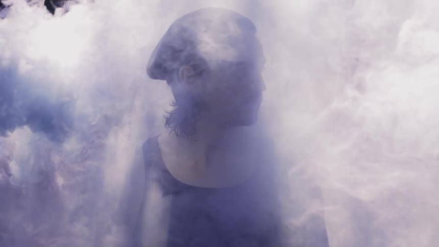 A man stands as he is covered in smoke
