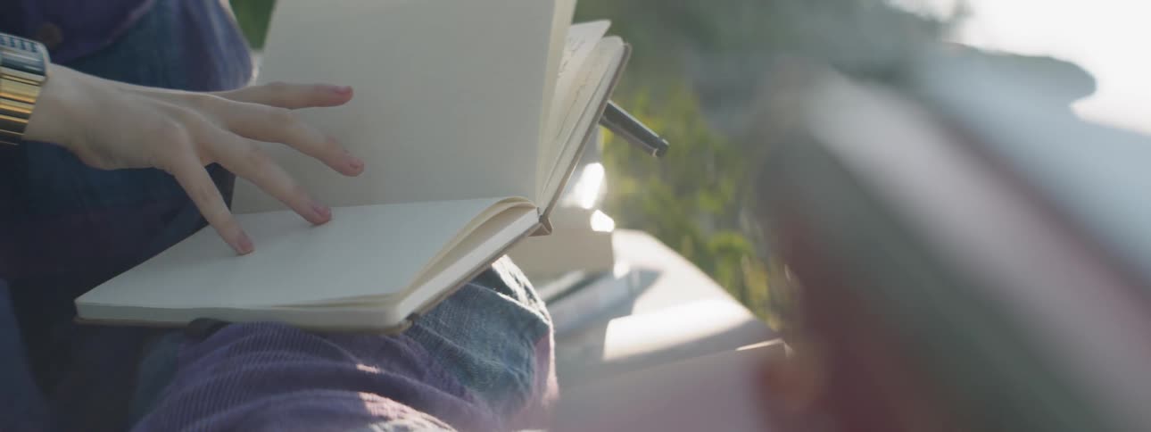A woman reads a book on a sofa outside