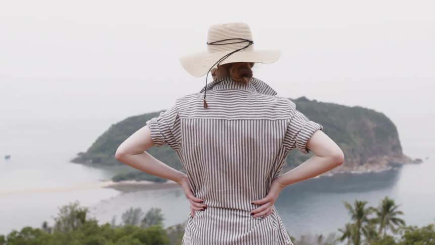Woman wearing a white hat looks out over the lake