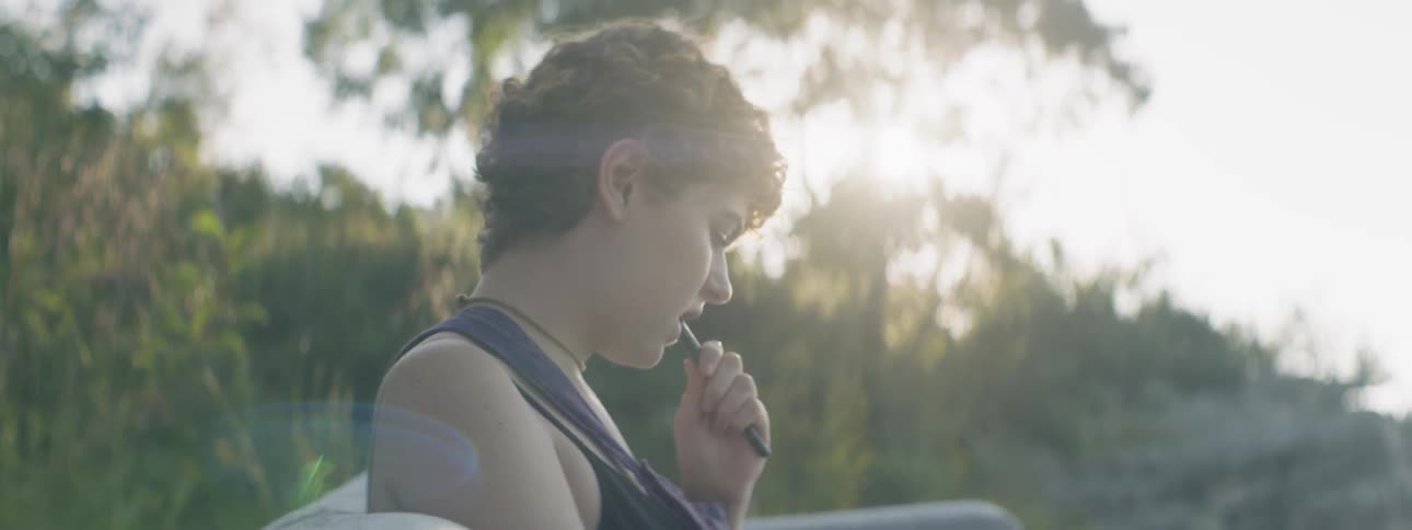 A woman bites her pen outside