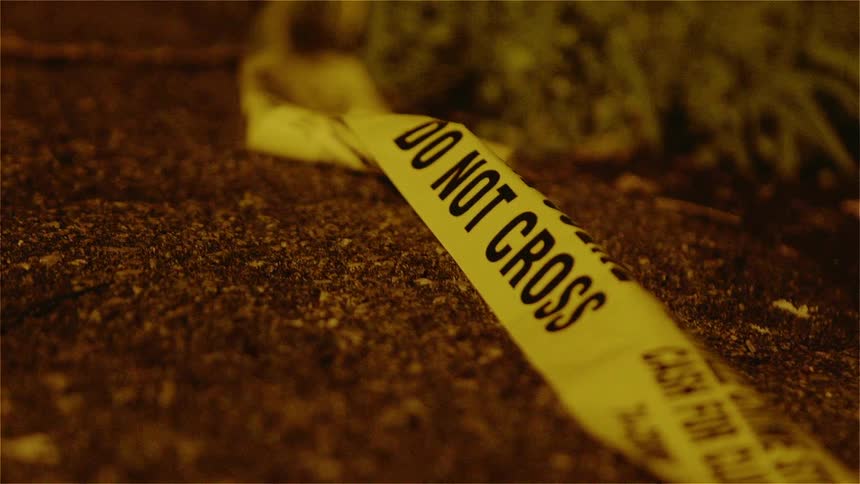 A yellow caution tape lays on the dirt