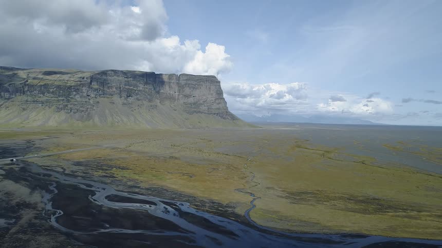 Clouds hang above the tall cliff and river