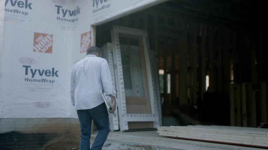 Man carries books and paper to a building under construction