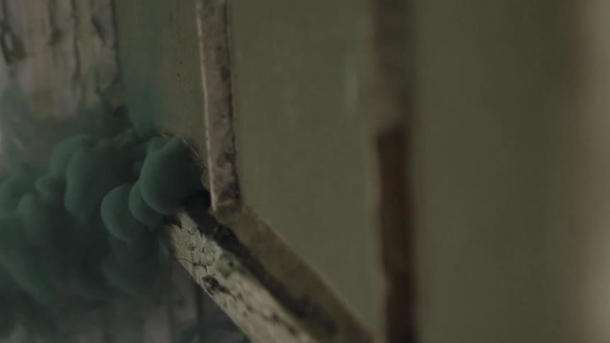 Smoke billows through a crack in a wall