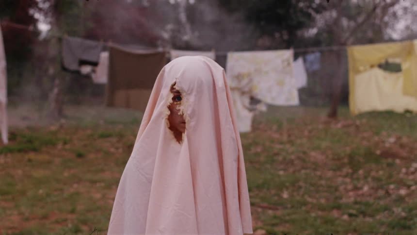 A child has a ripped blanket on his head