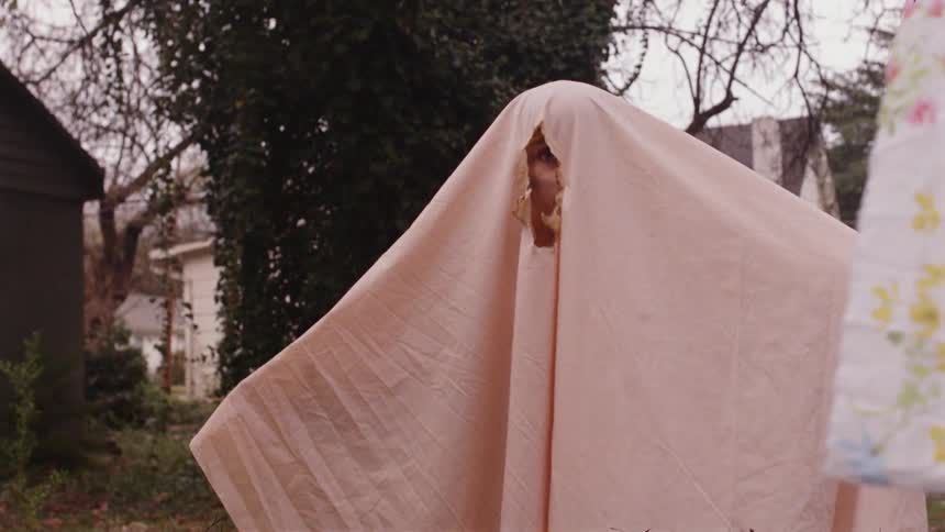 A person is hiding under a sheet outside on a smoky day