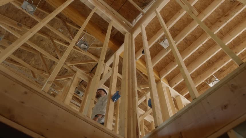 A man walks upstairs in the unfinished house