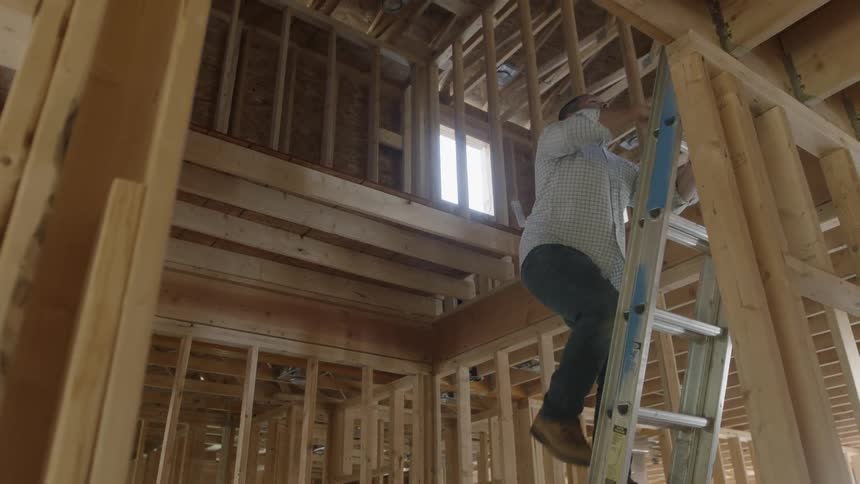 Man is climbing ladder inside construction building