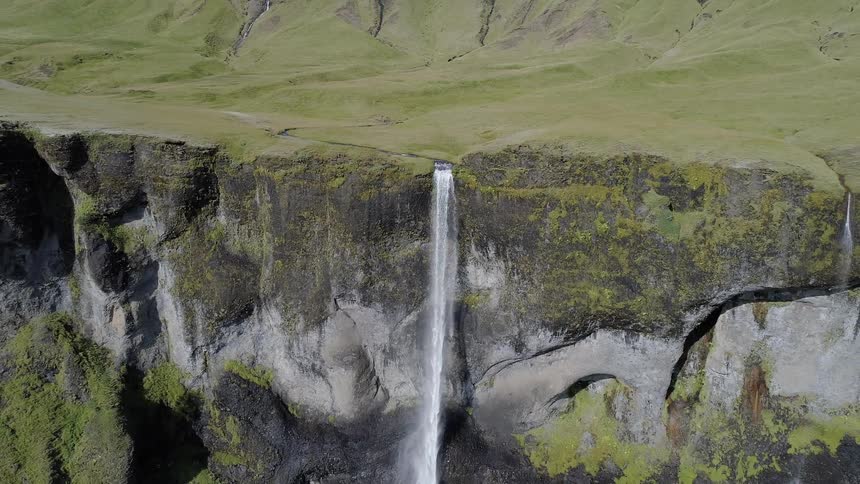 A waterfall flows over a cliff in the wilderness