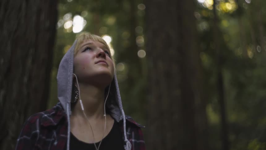 A woman looks upwards in the forest