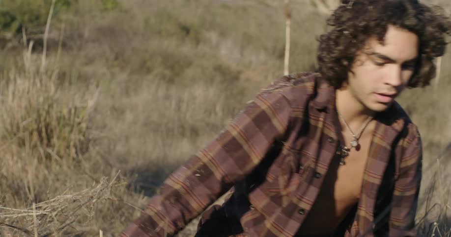 A man searches through grass in a rural field and collapses