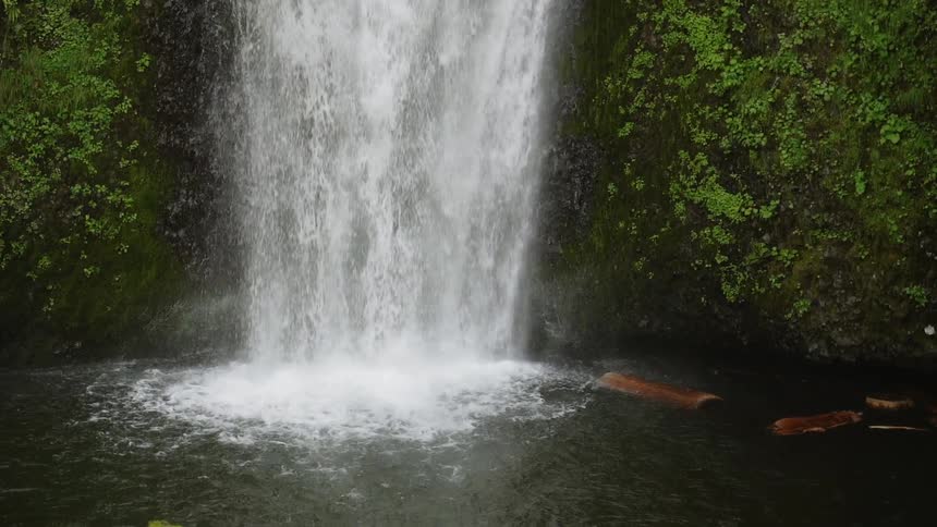 Waterfall flowing off edge of rock cliff into river pool