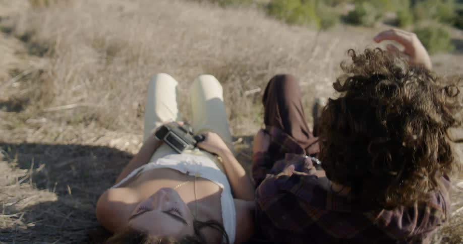 A man and woman lay together in the grass