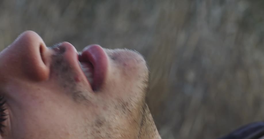 A man is lying on the ground gasping for breath in a natural setting in daylight