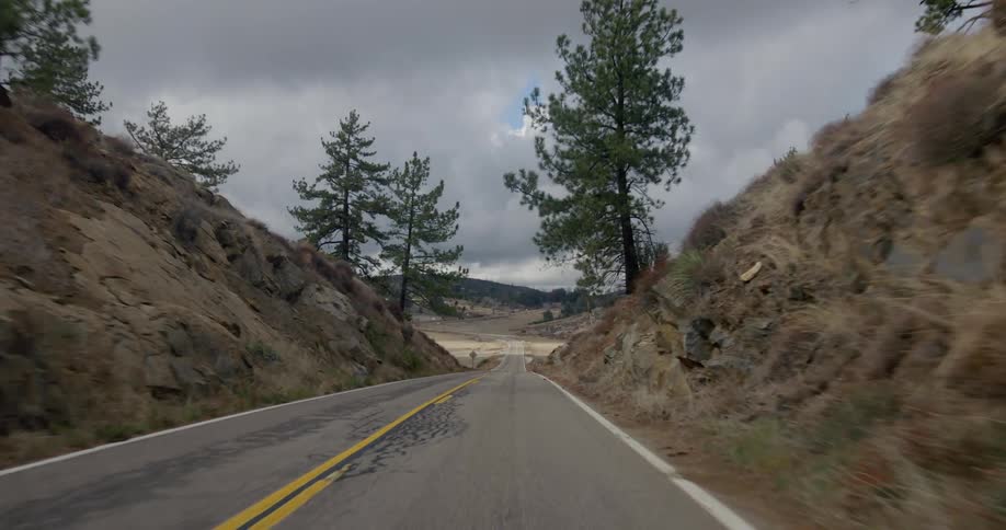 A vehicle travels on a road in the wilderness