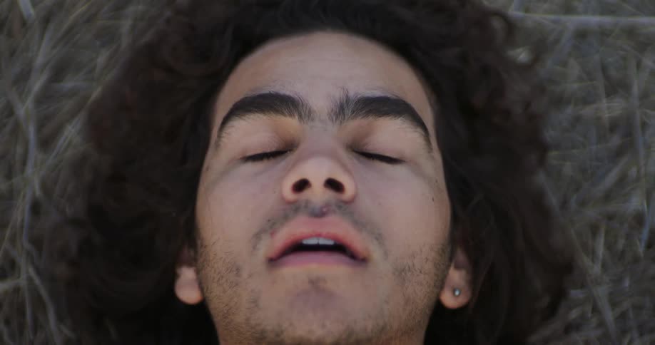 A man lays on the ground and closes his eyes