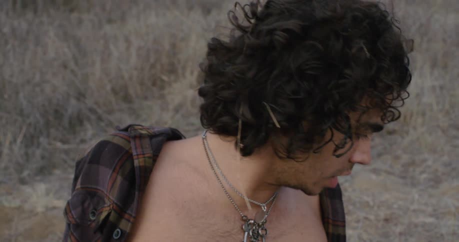 A man lying on the ground is startling awake outside in daylight