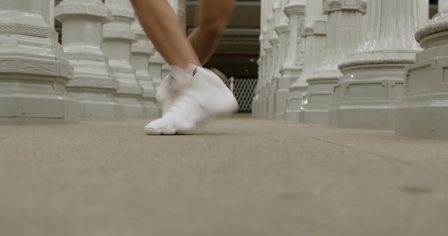 The legs of a girl performing dance steps in between white posts